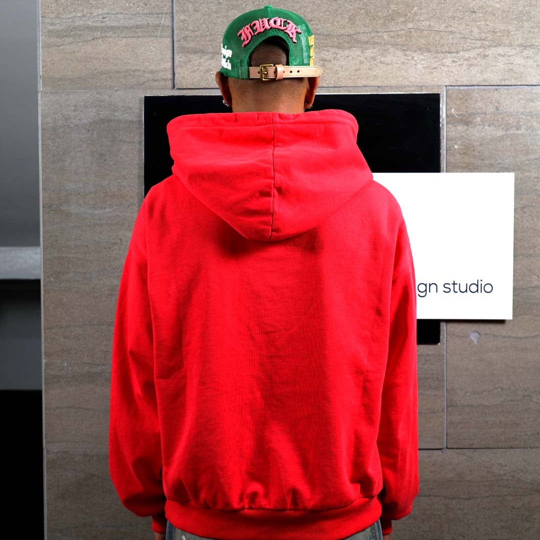 Person in red hoodie facing wall.