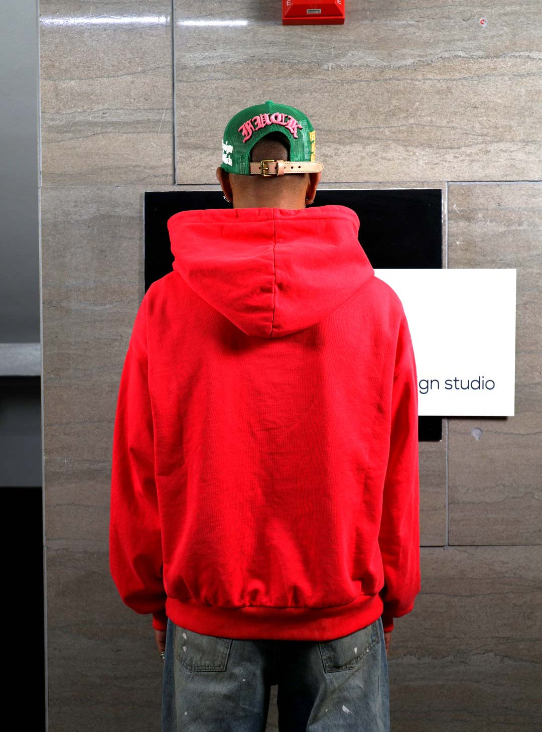 Person in red hoodie facing wall.