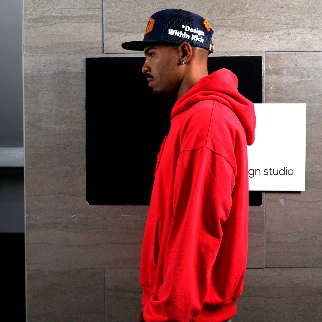 Man in red hoodie and cap, side profile.