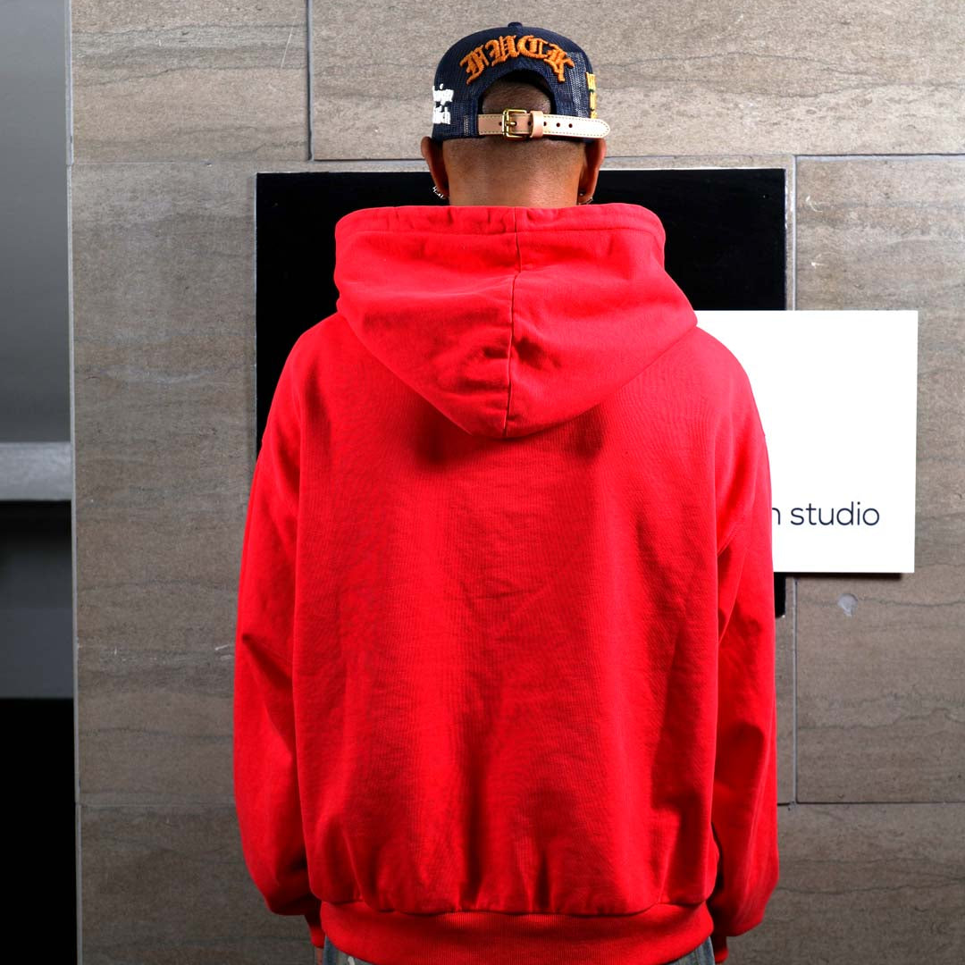 Person in red hoodie facing wall.