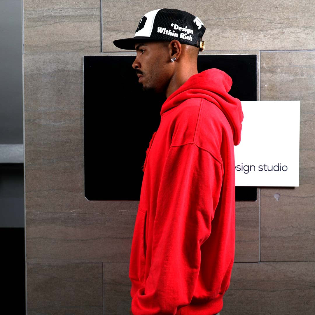 Man in red hoodie and cap, side profile.