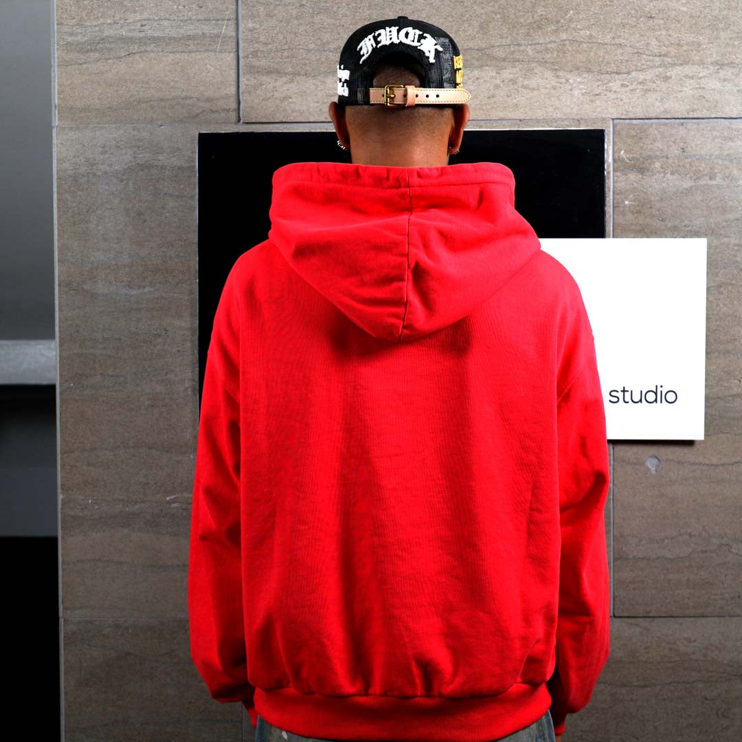 Person in red hoodie facing wall.