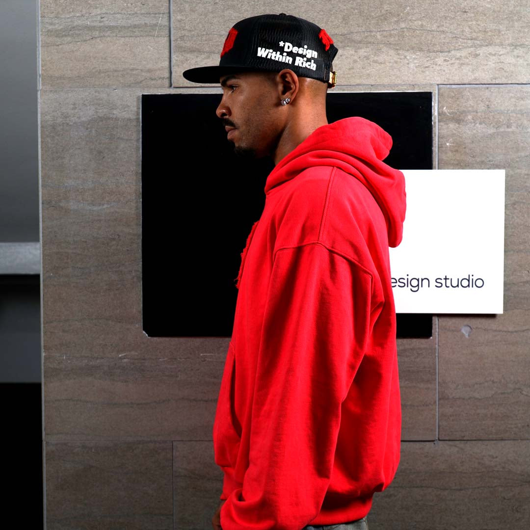 Man in red hoodie and cap, side profile.