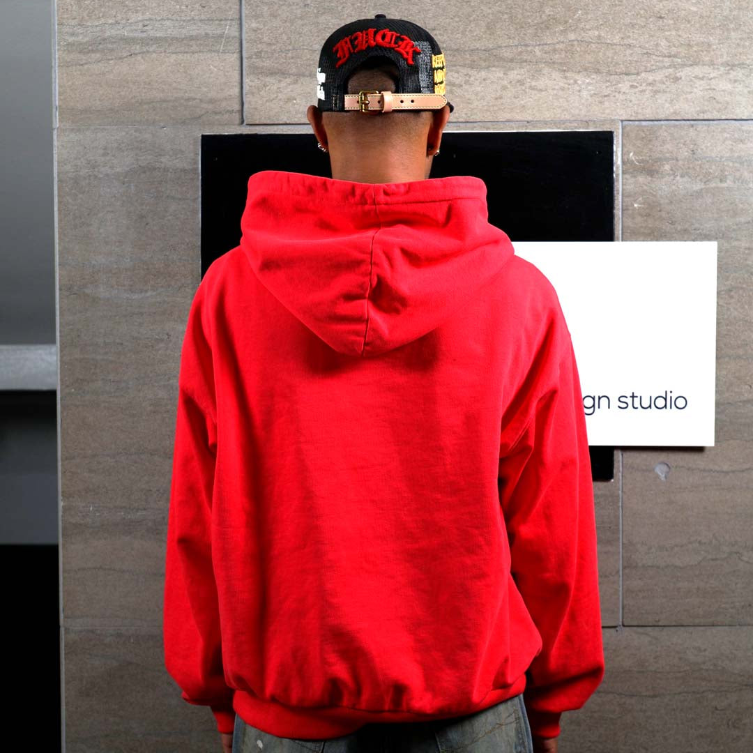 Person in red hoodie facing wall.