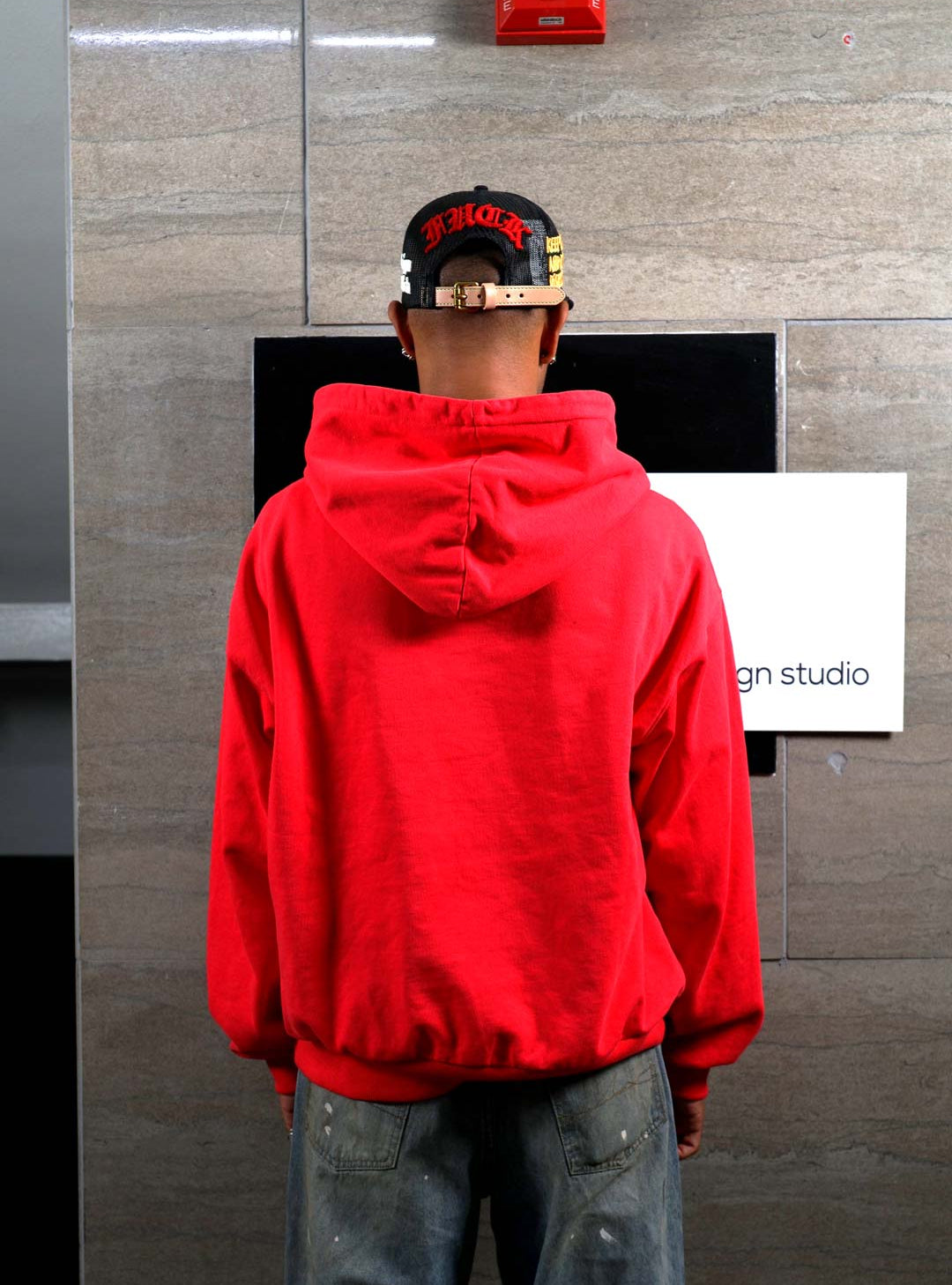 Person in red hoodie facing wall.
