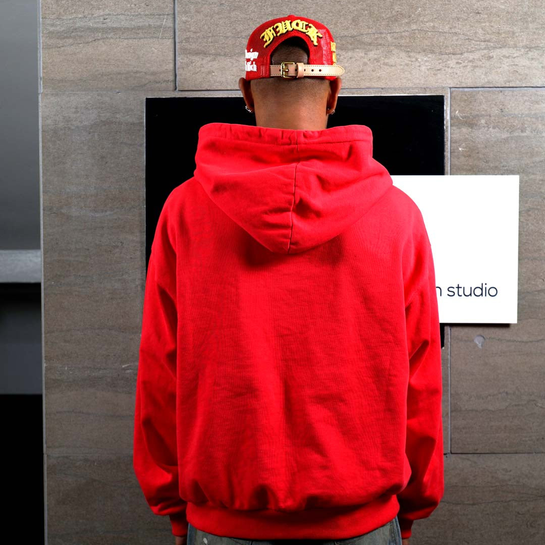 Person in red hoodie facing wall.