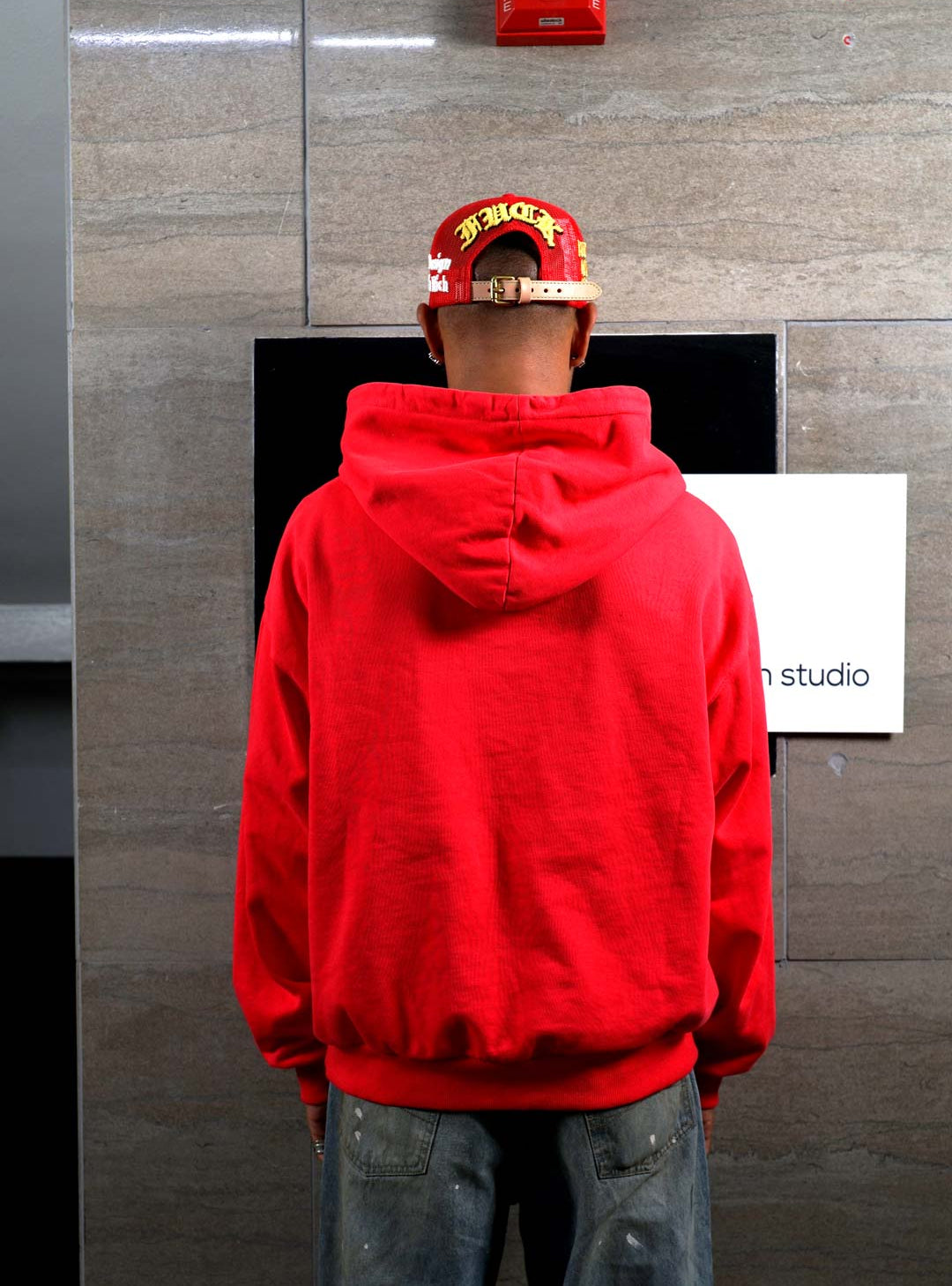 Person in red hoodie facing wall.