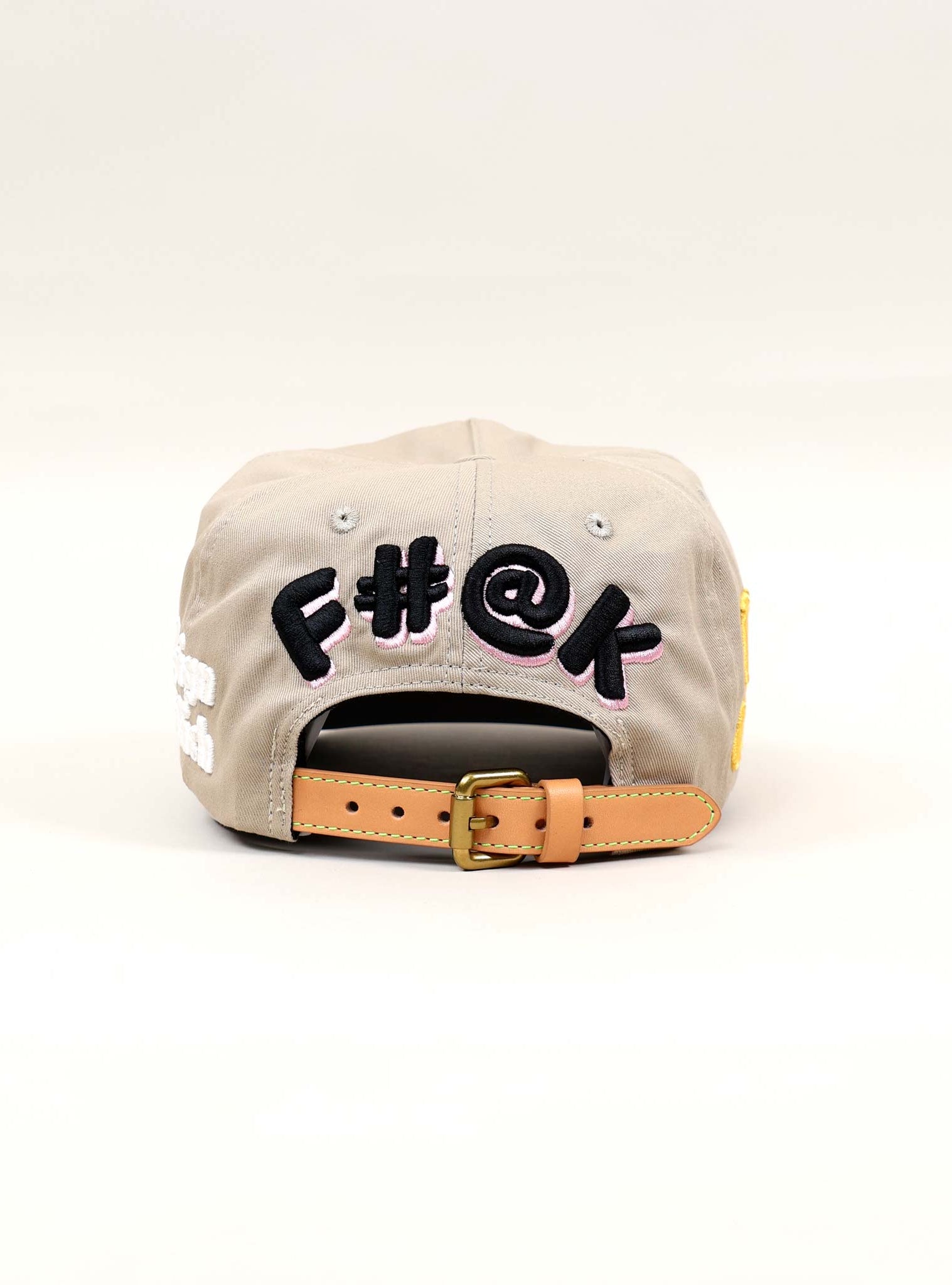 Back view of a beige cap with embroidered text.