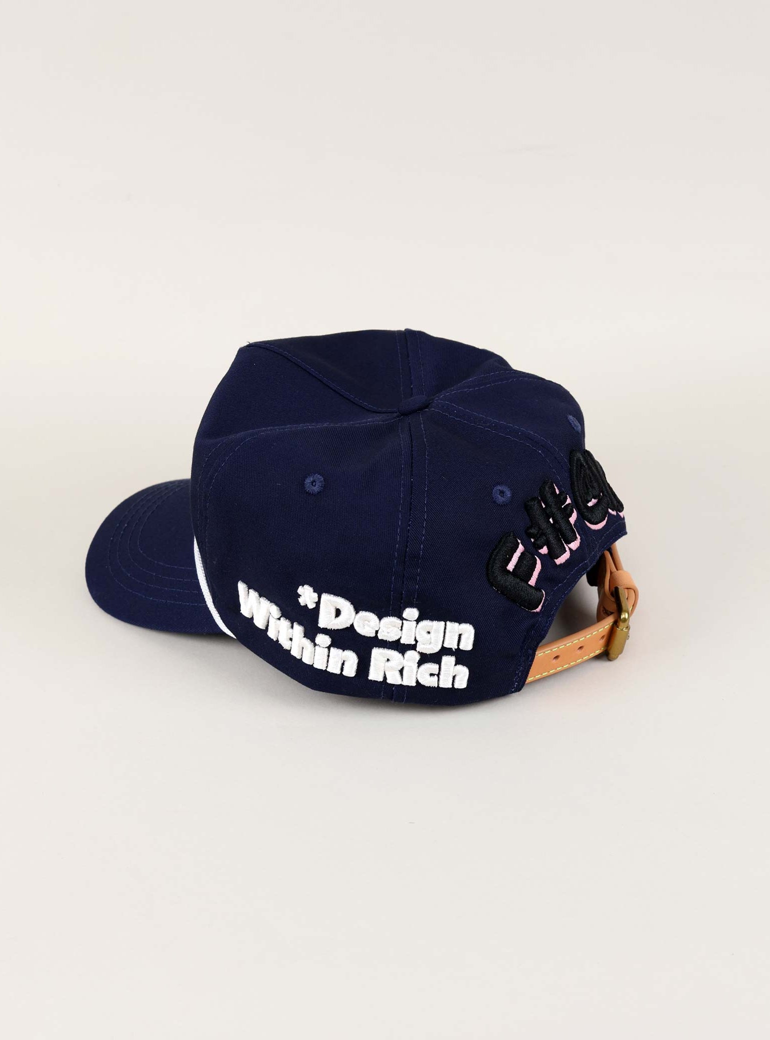 Navy cap with "Design Within Rich" text.