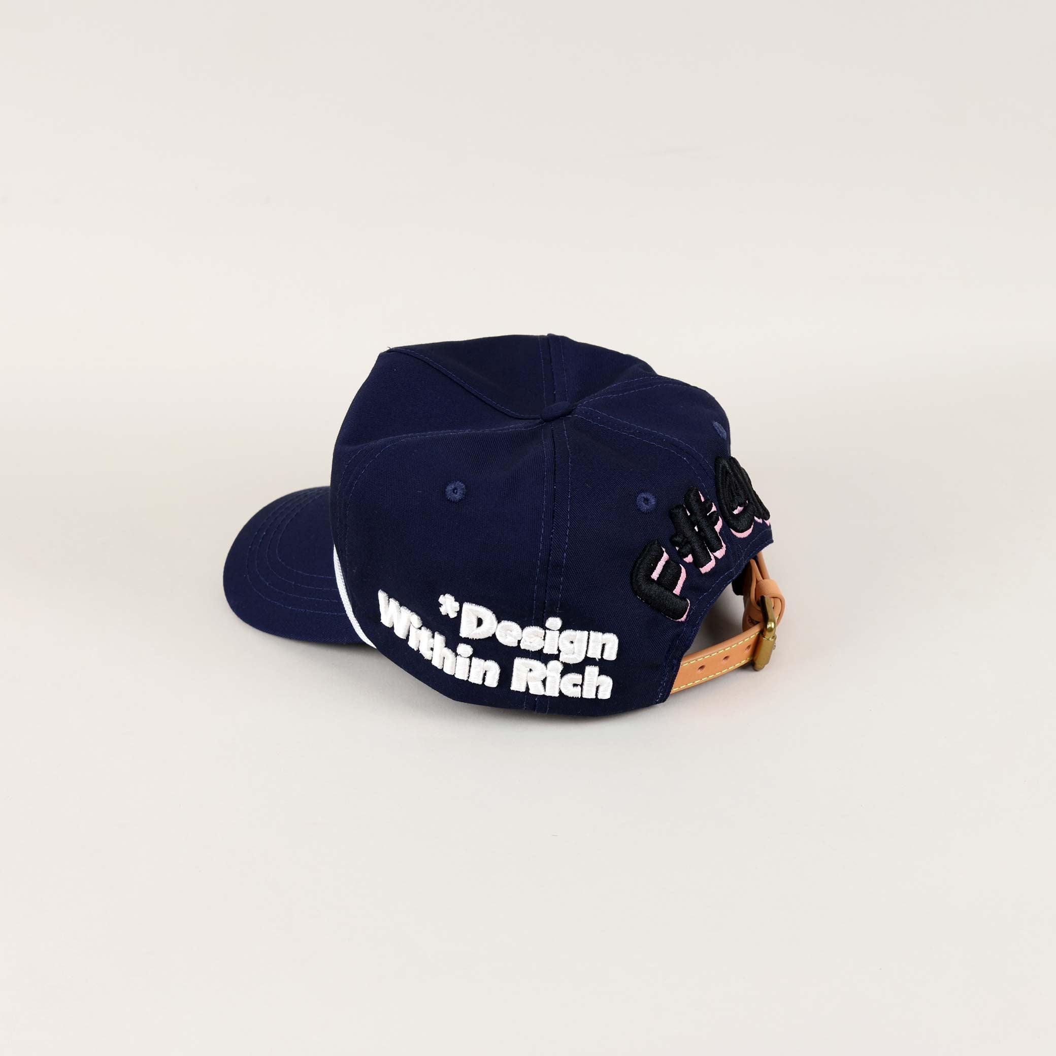 Navy cap with "Design Within Rich" text.