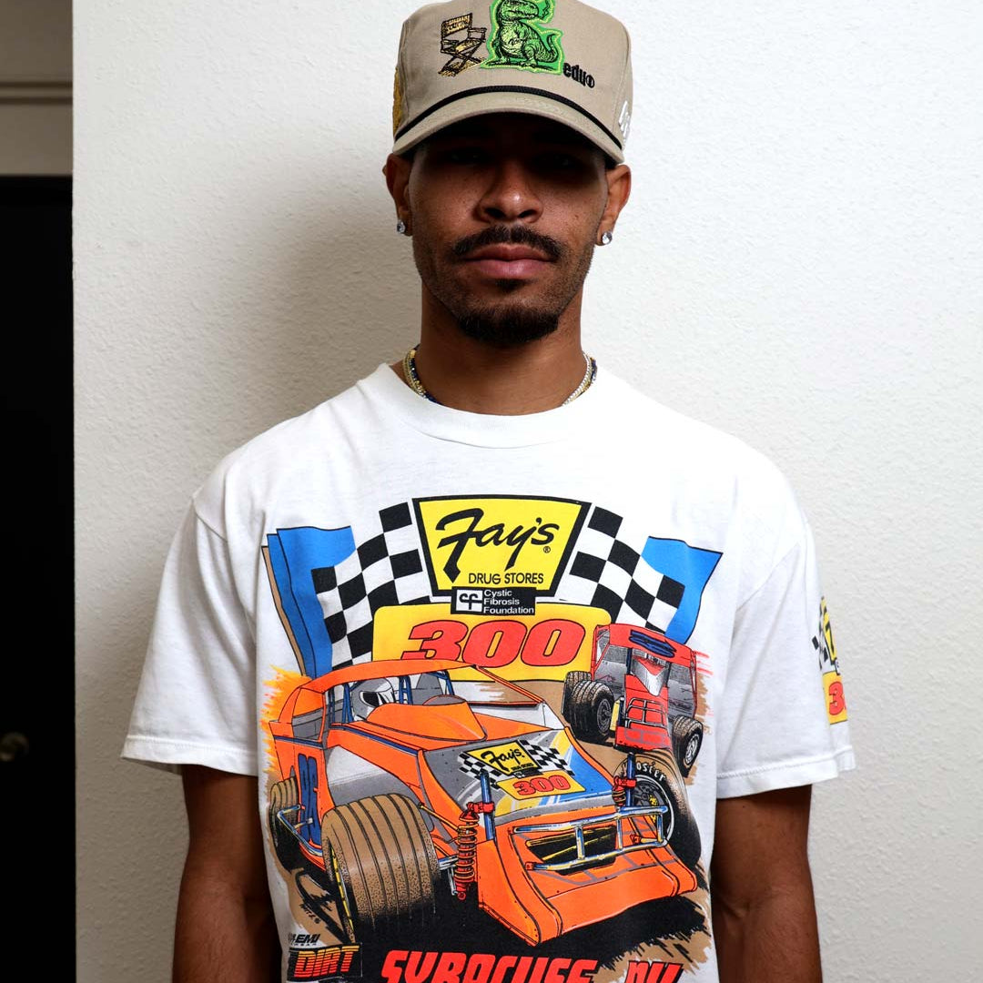 Man wearing graphic racing shirt and cap.