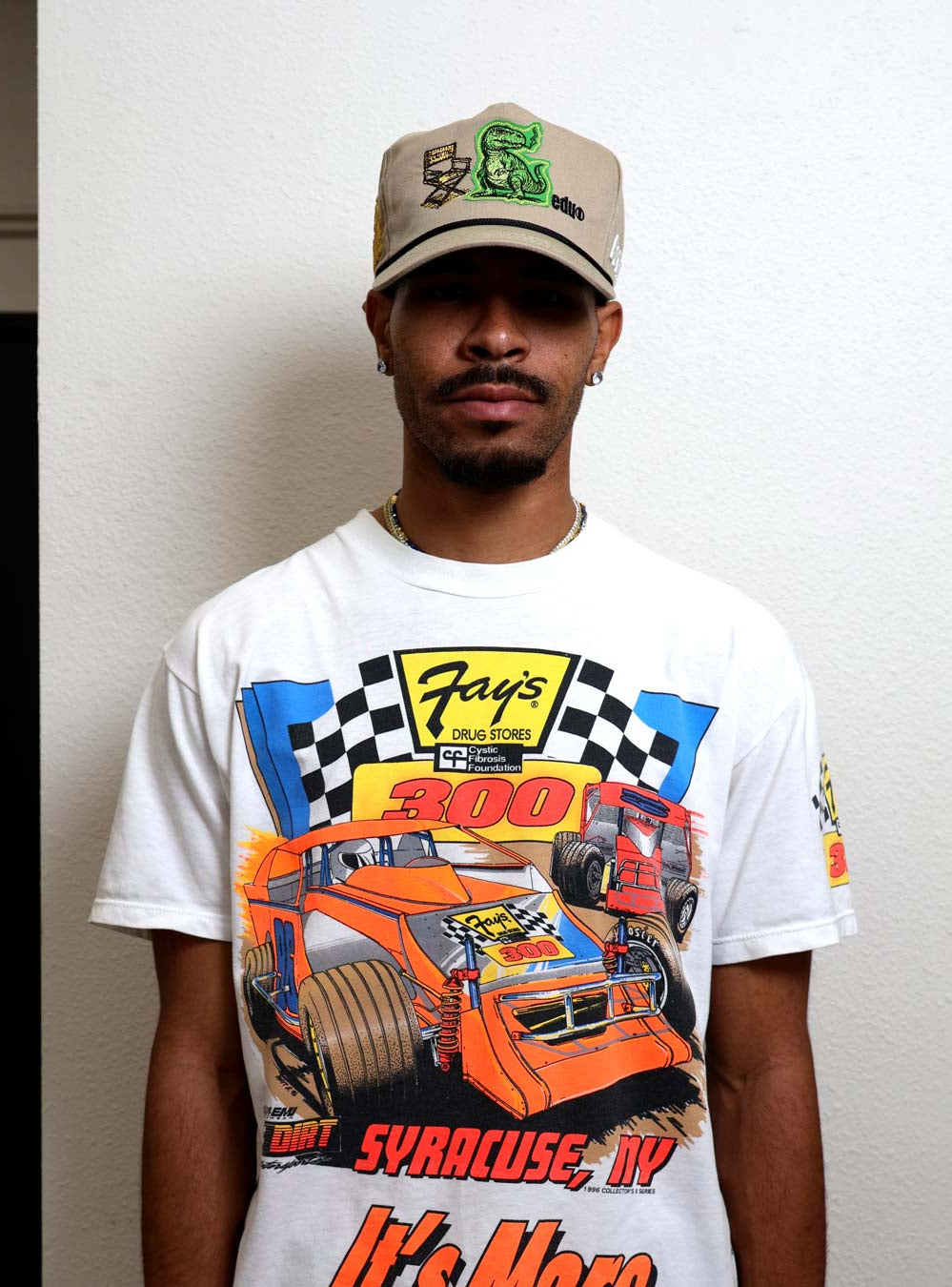 Man wearing graphic racing shirt and cap.