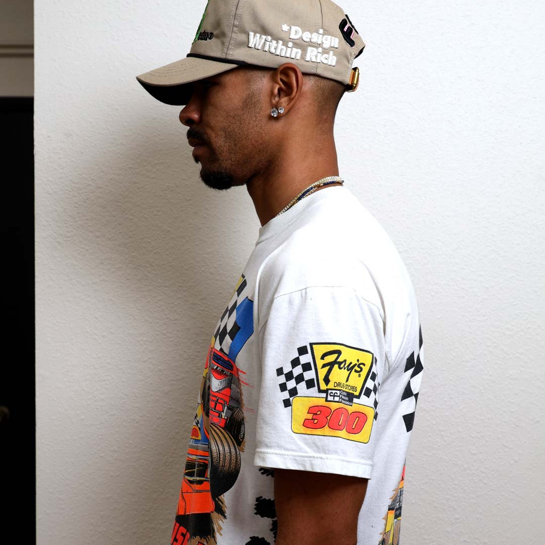 Man in graphic t-shirt and beige cap.