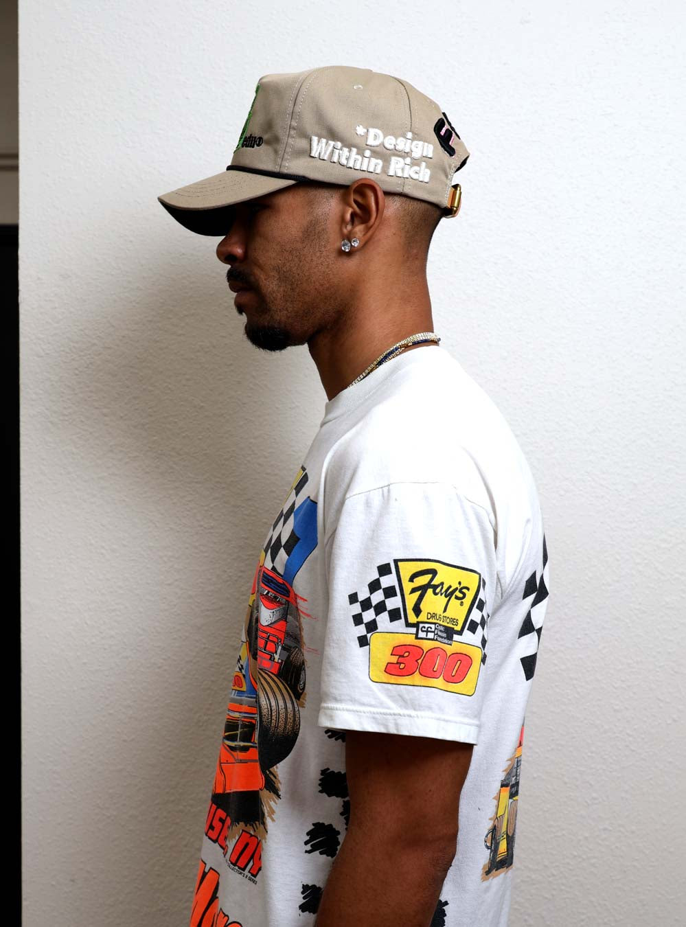 Man in graphic t-shirt and beige cap.