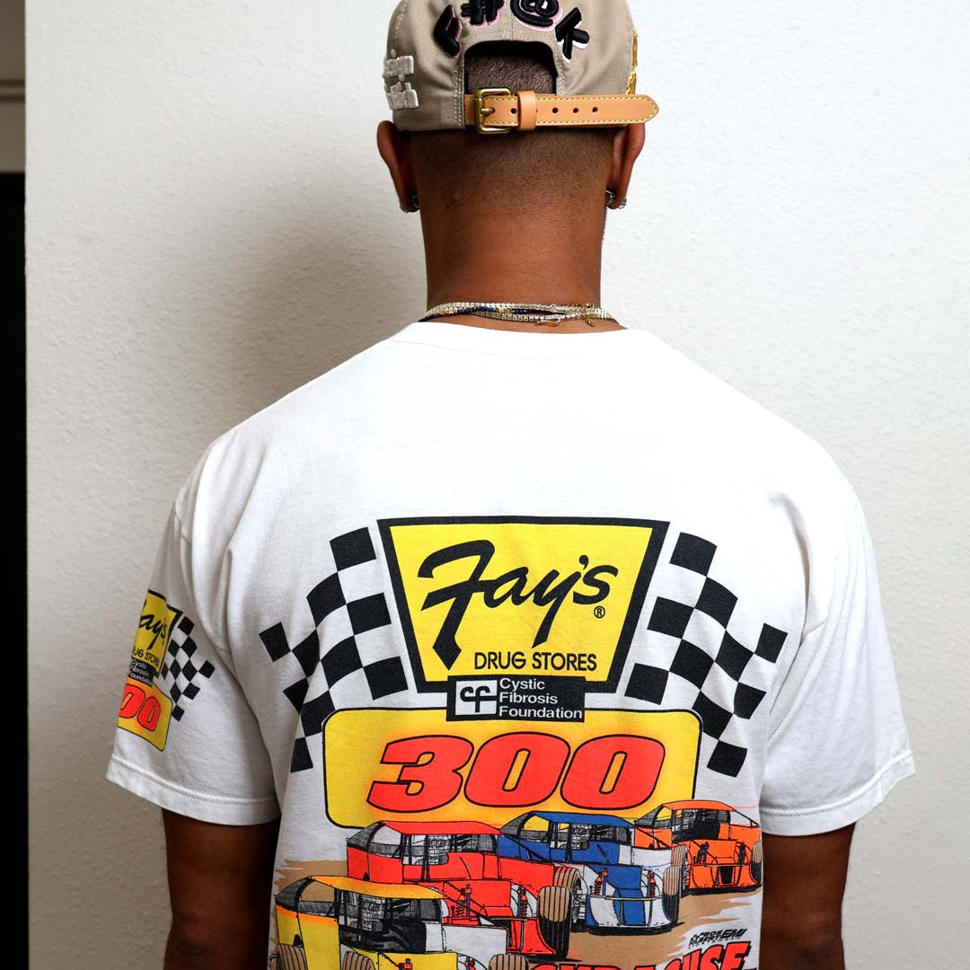 Man wearing racing-themed shirt and cap, back view.