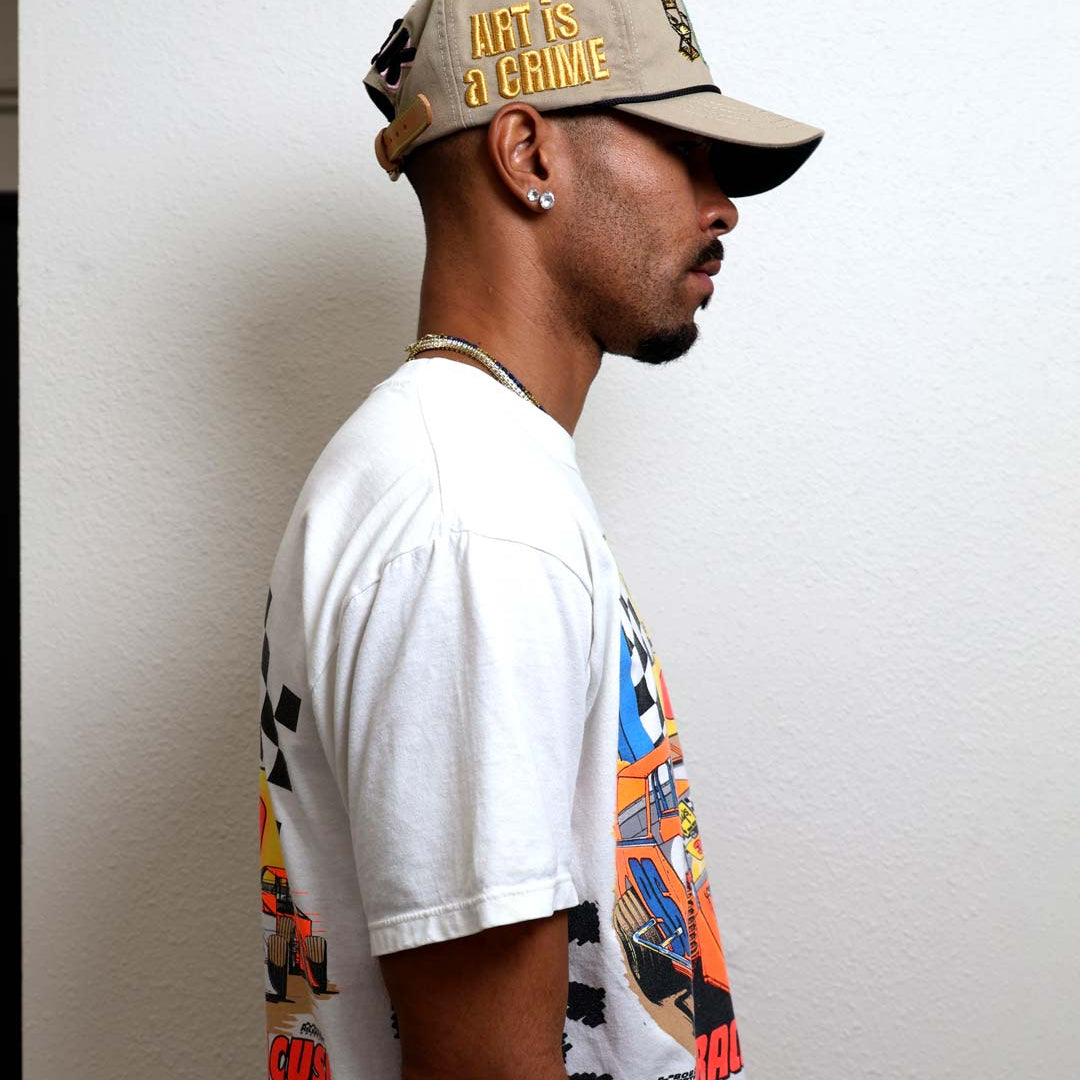 Man in graphic tee and cap facing sideways.