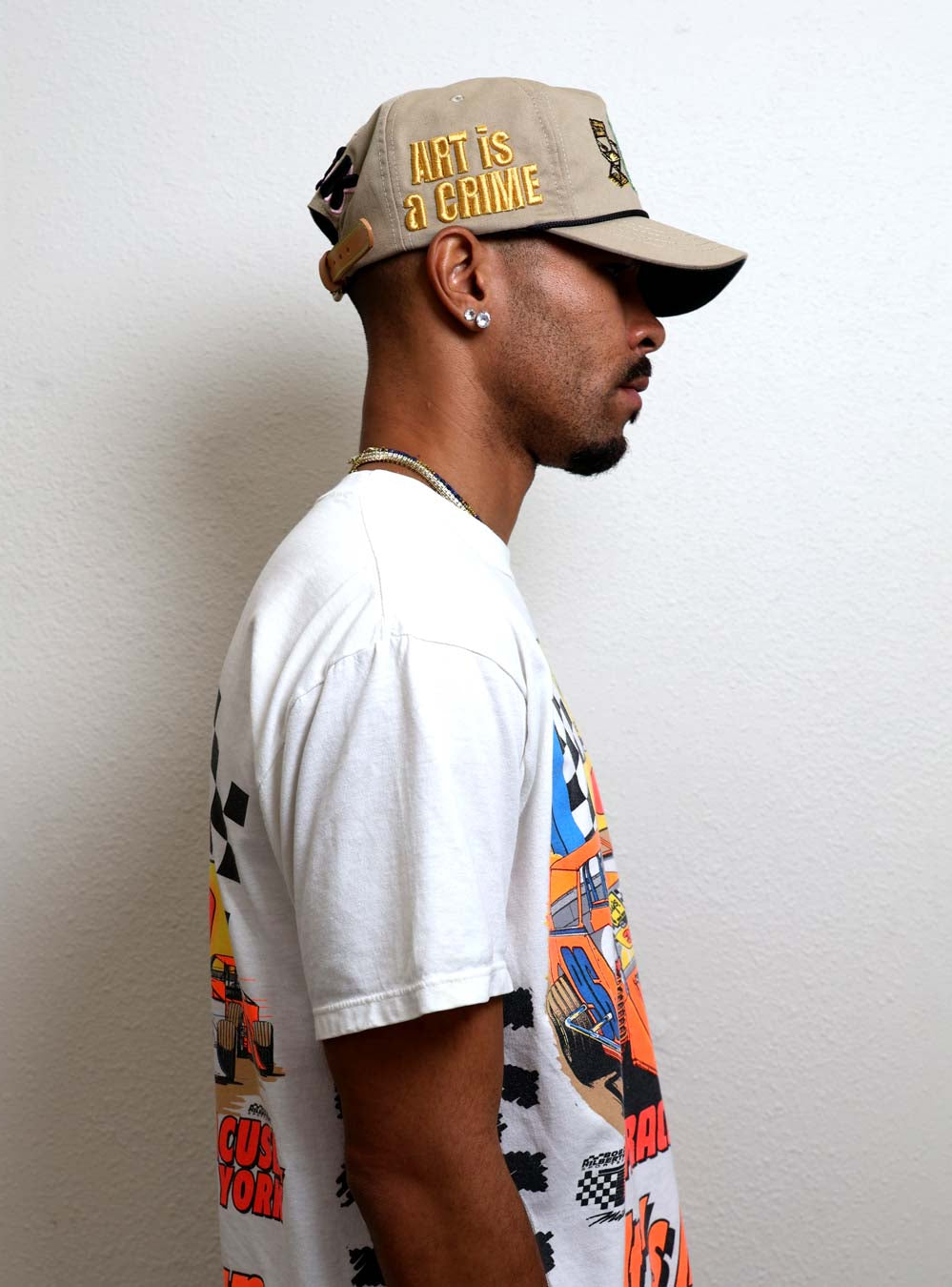 Man in graphic tee and cap facing sideways.