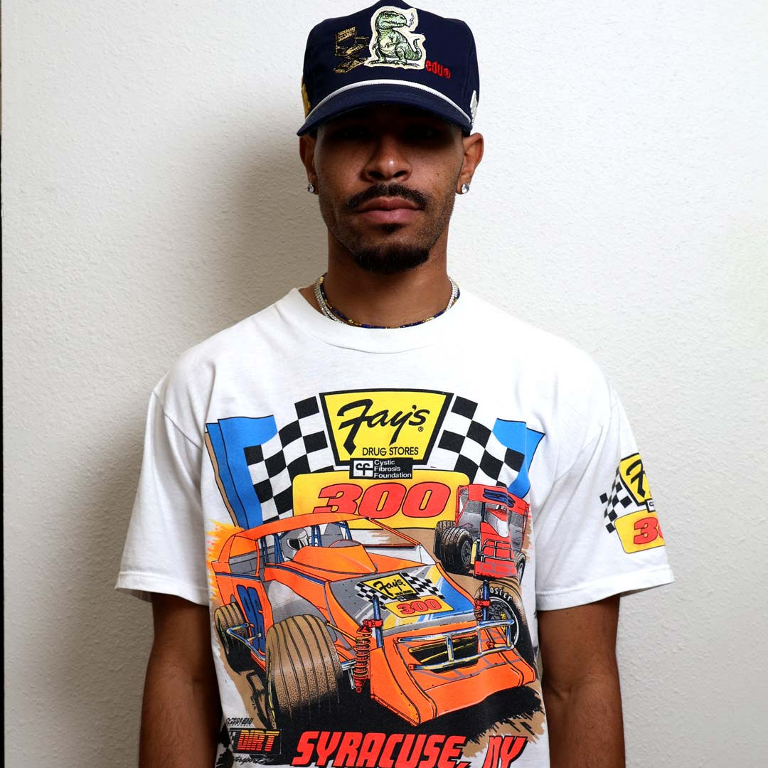 Man wearing racing-themed shirt and cap.