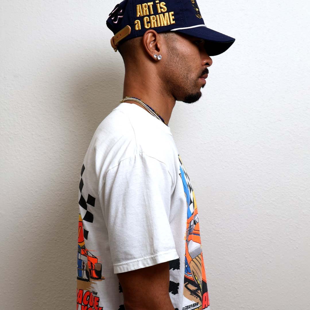 Man in graphic tee and cap, side profile.