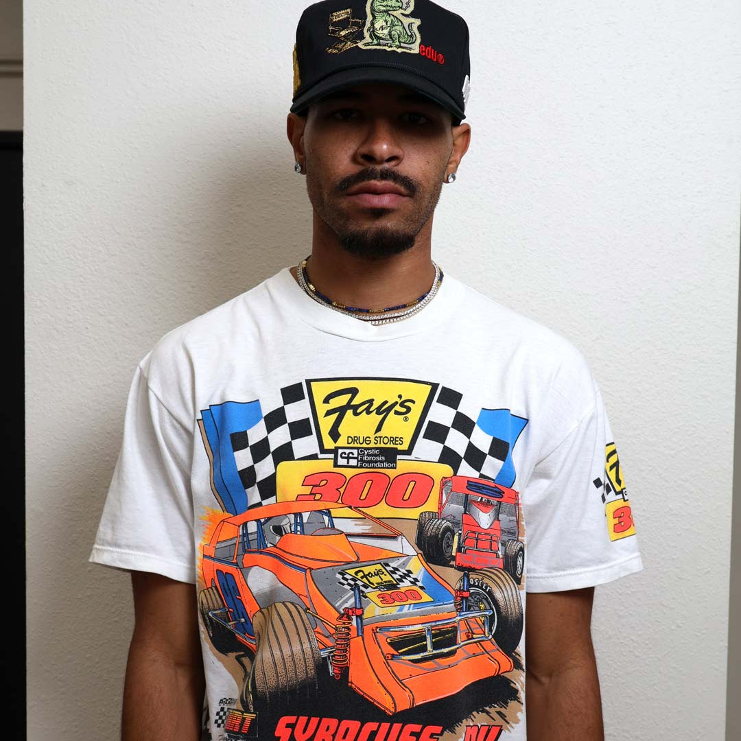 Man wearing a racing-themed shirt and cap.