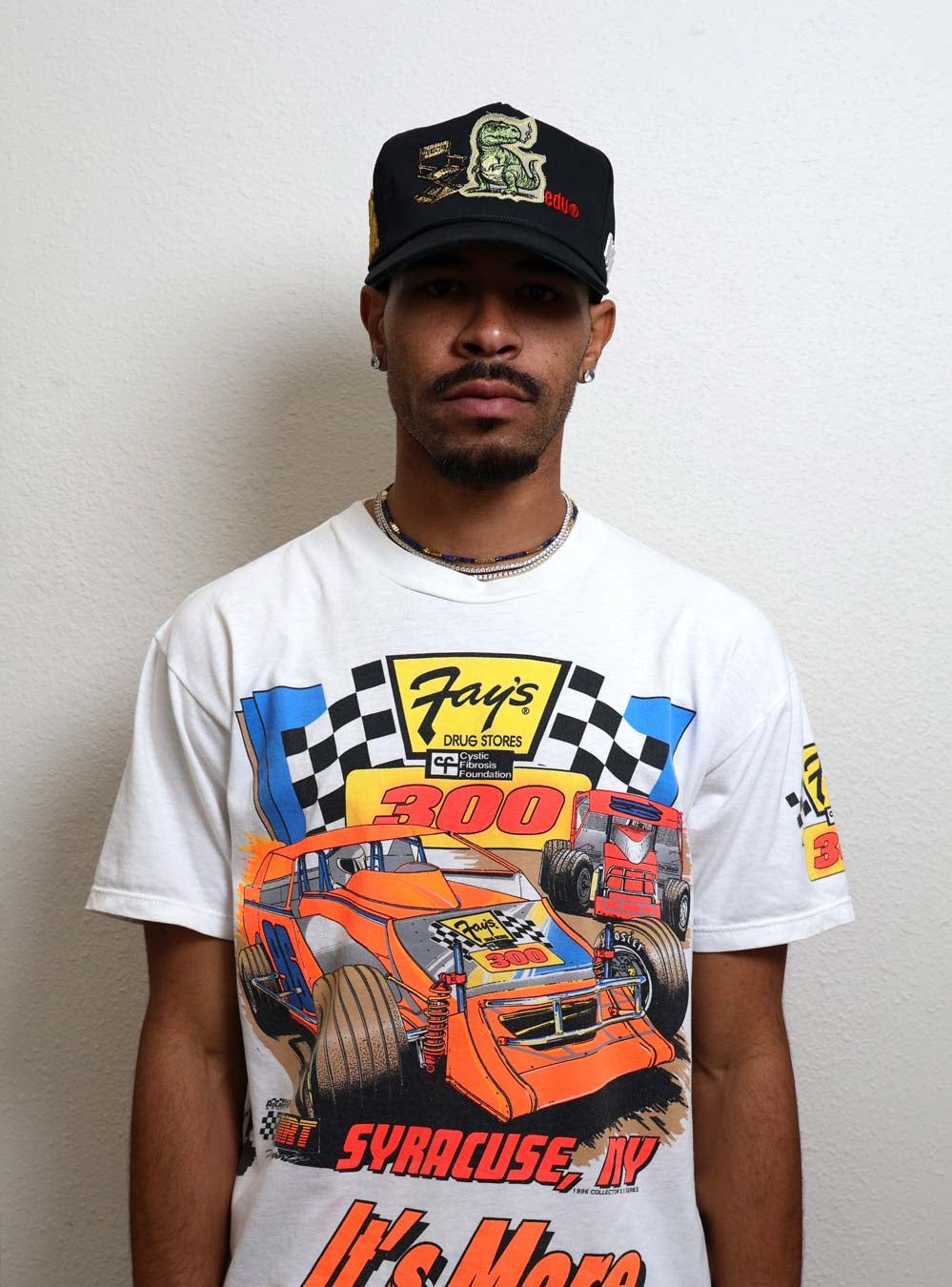 Man wearing a racing-themed shirt and cap.