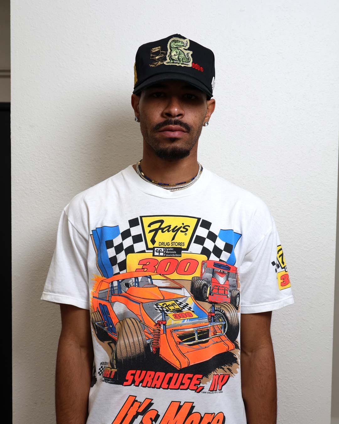 Man wearing a racing-themed shirt and cap.
