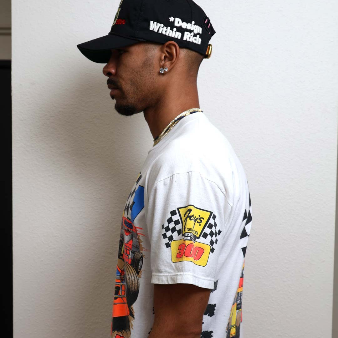 Man in graphic t-shirt and cap, side profile.