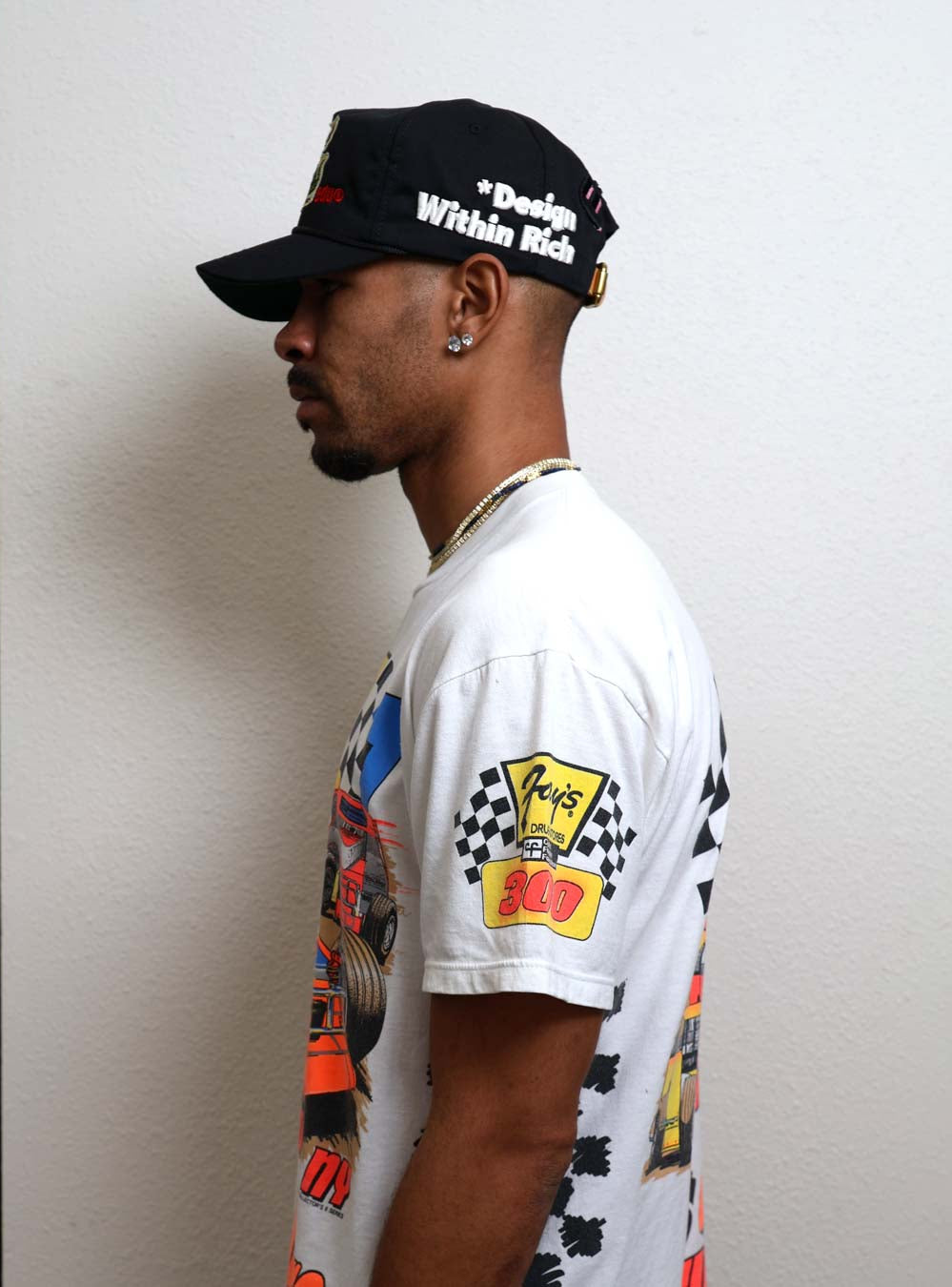 Man in graphic t-shirt and cap, side profile.