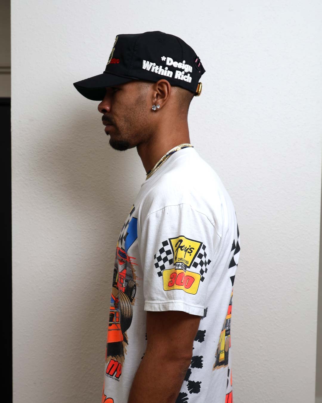 Man in graphic t-shirt and cap, side profile.