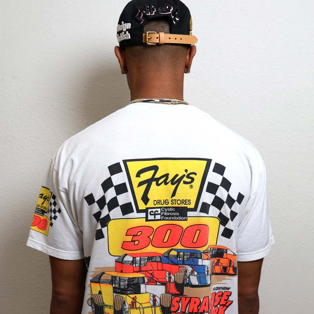 Man wearing graphic racing-themed shirt and cap.