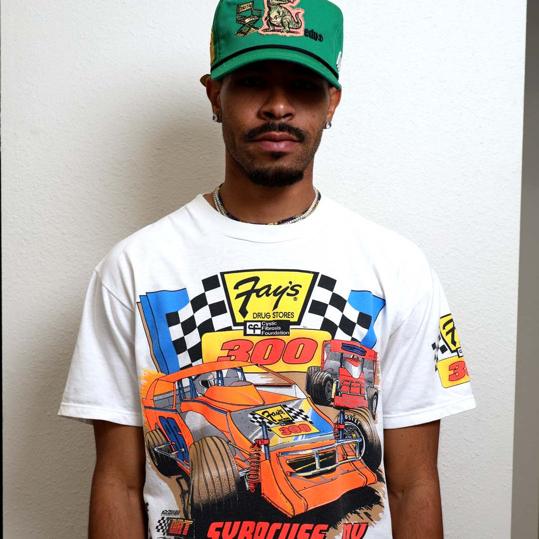 Man wearing graphic t-shirt and green cap.