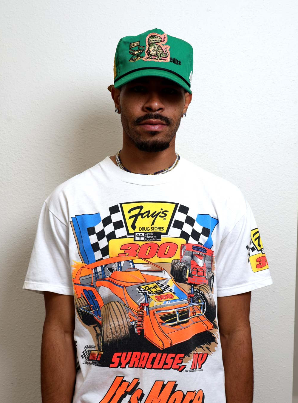 Man wearing graphic t-shirt and green cap.