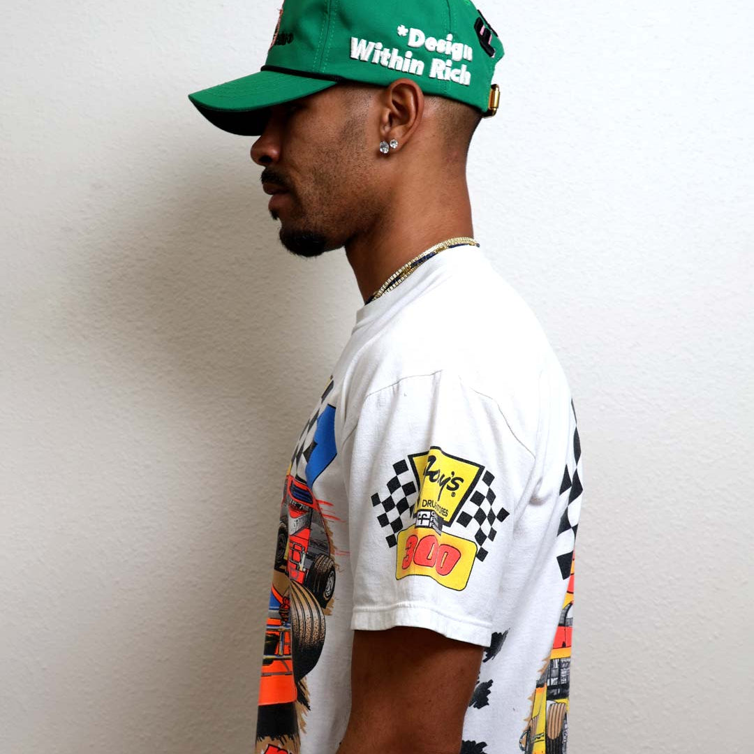 Man in green cap and graphic t-shirt.