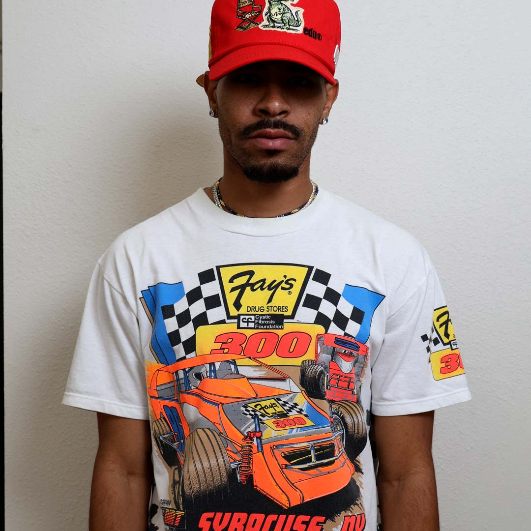 Man wearing racing-themed shirt and red cap.