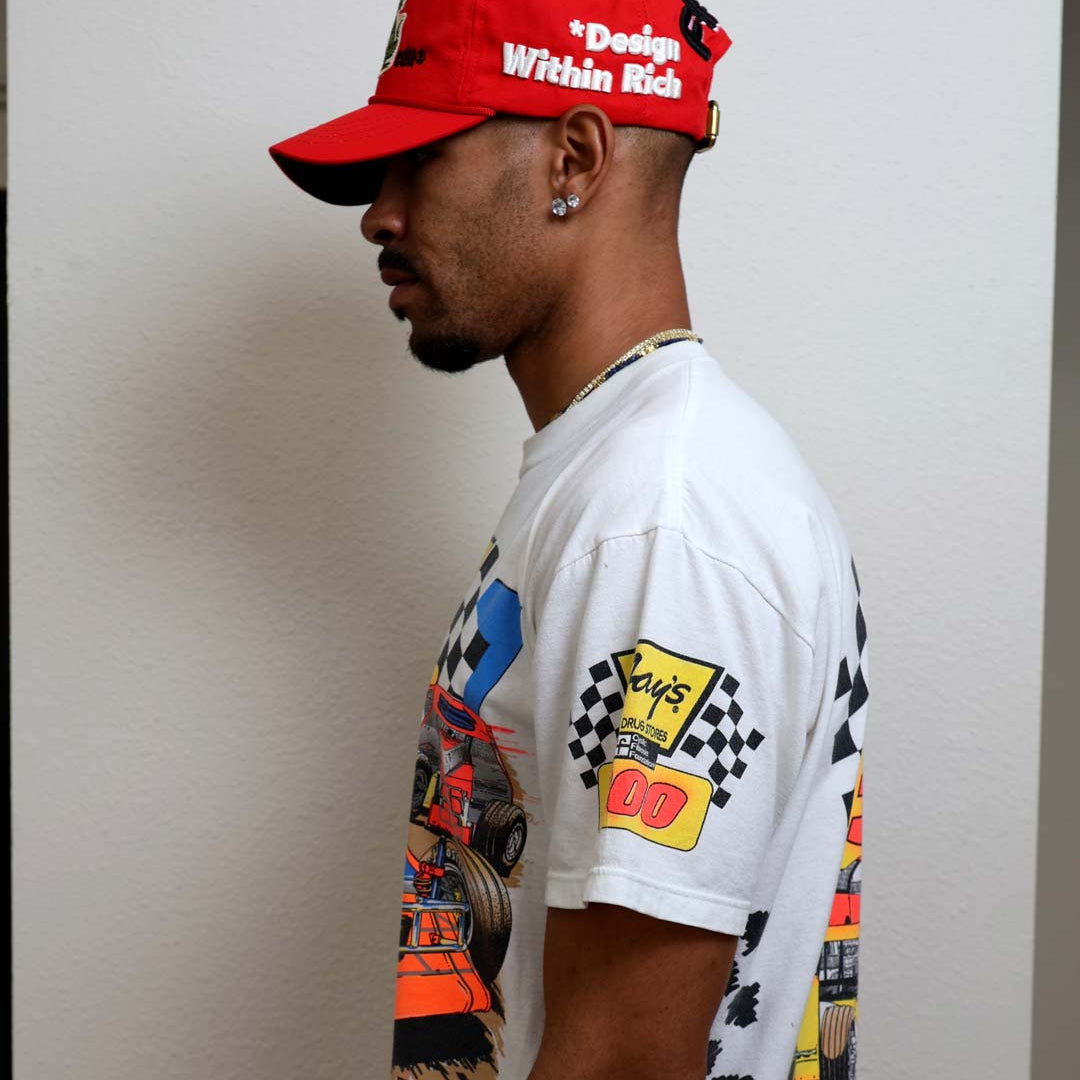 Man in graphic tee and red cap, side view.