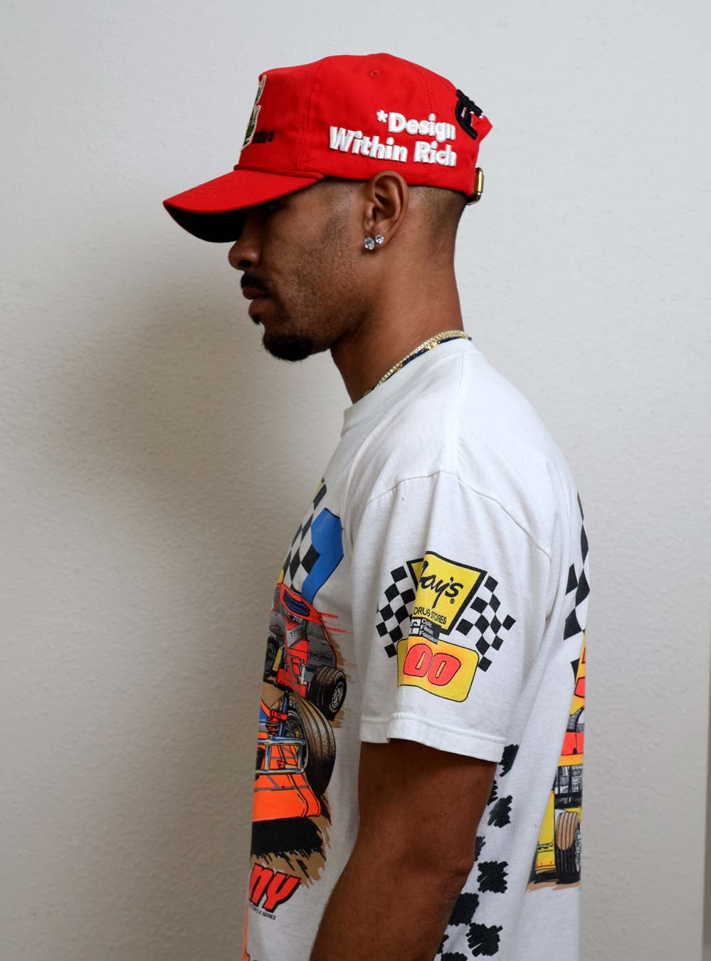 Man in graphic tee and red cap, side view.
