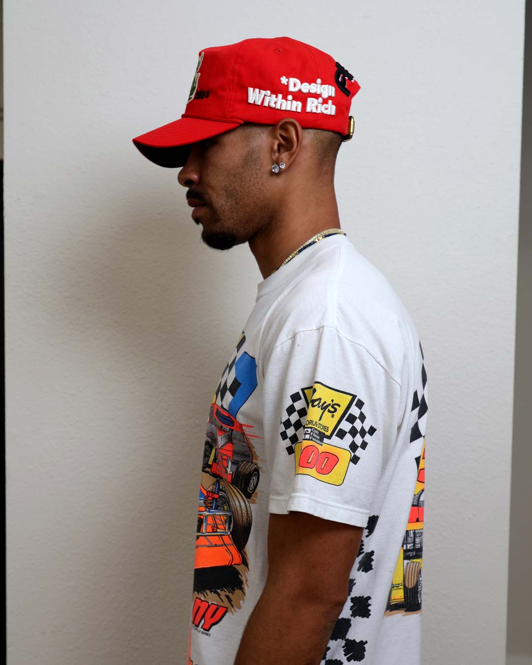 Man in graphic tee and red cap, side view.