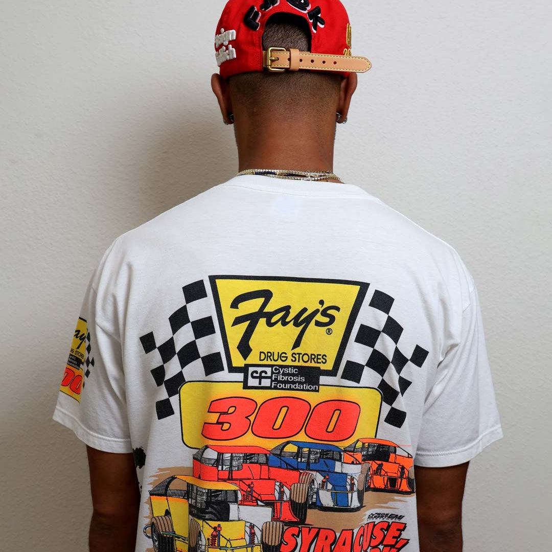 Man wearing graphic racing-themed shirt and red cap.