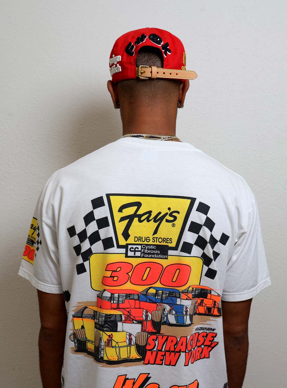 Man wearing graphic racing-themed shirt and red cap.