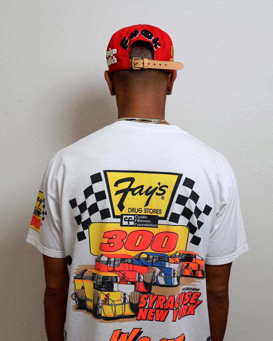 Man wearing graphic racing-themed shirt and red cap.