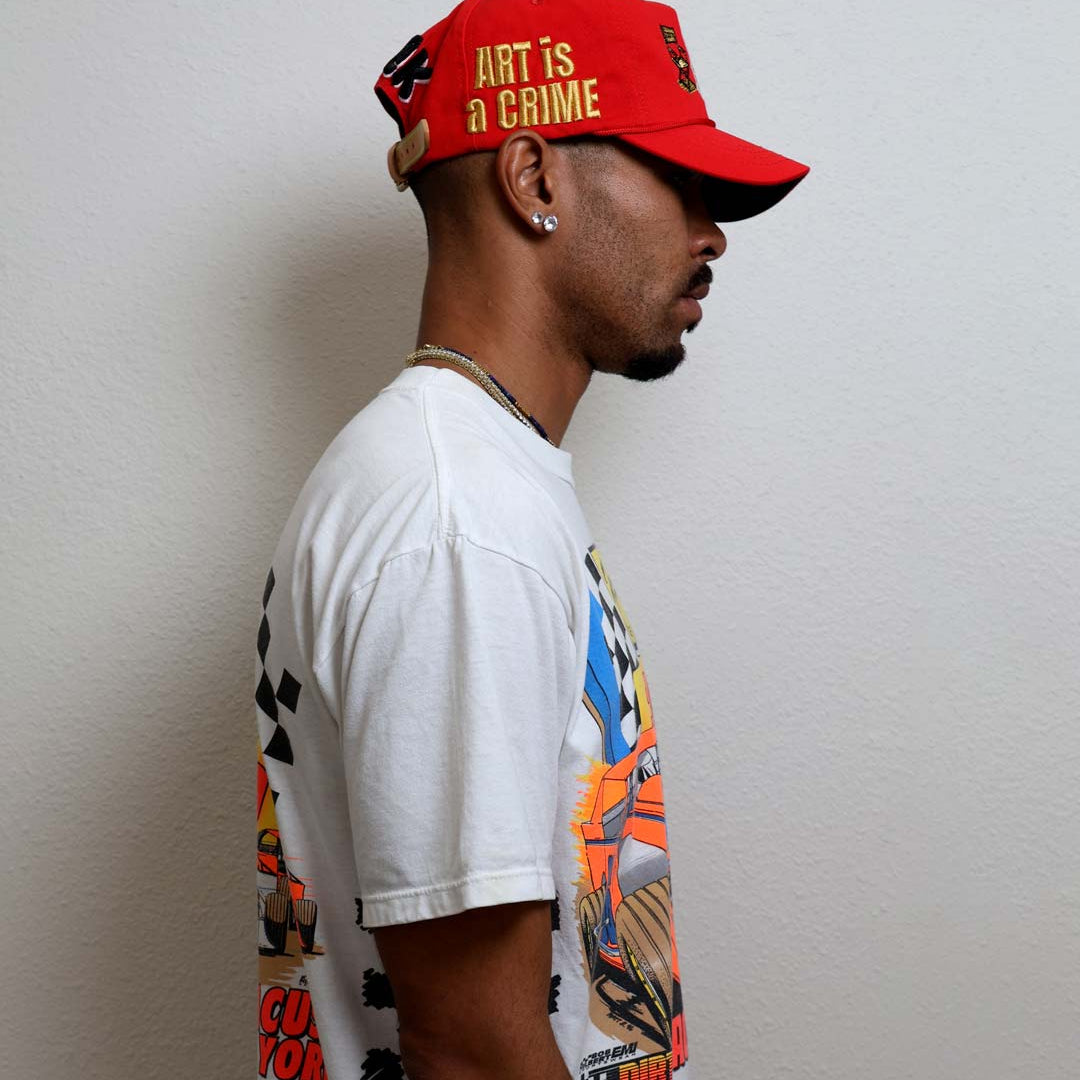 Man wearing graphic t-shirt and red cap.