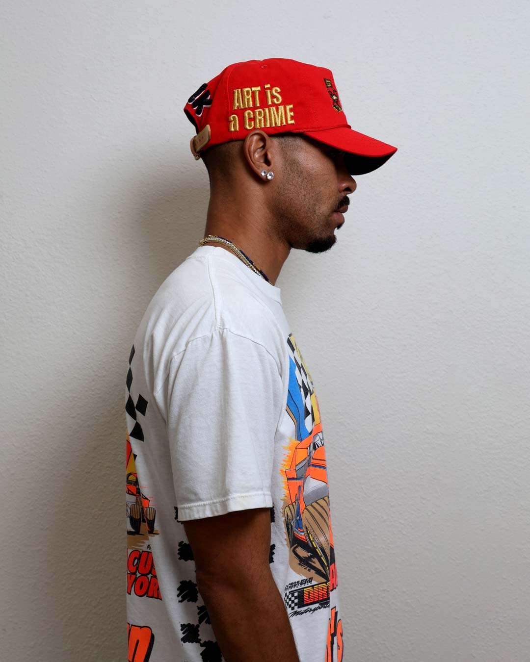 Man in graphic tee and red cap, side view.