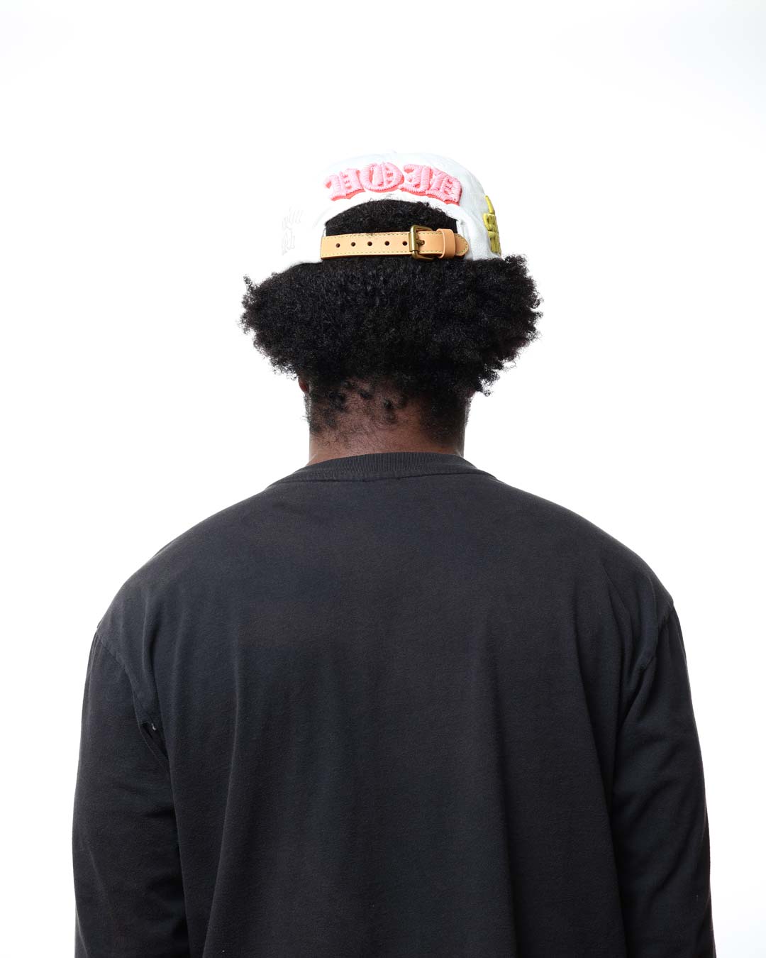 Person wearing a black shirt and colorful cap with text on a white background