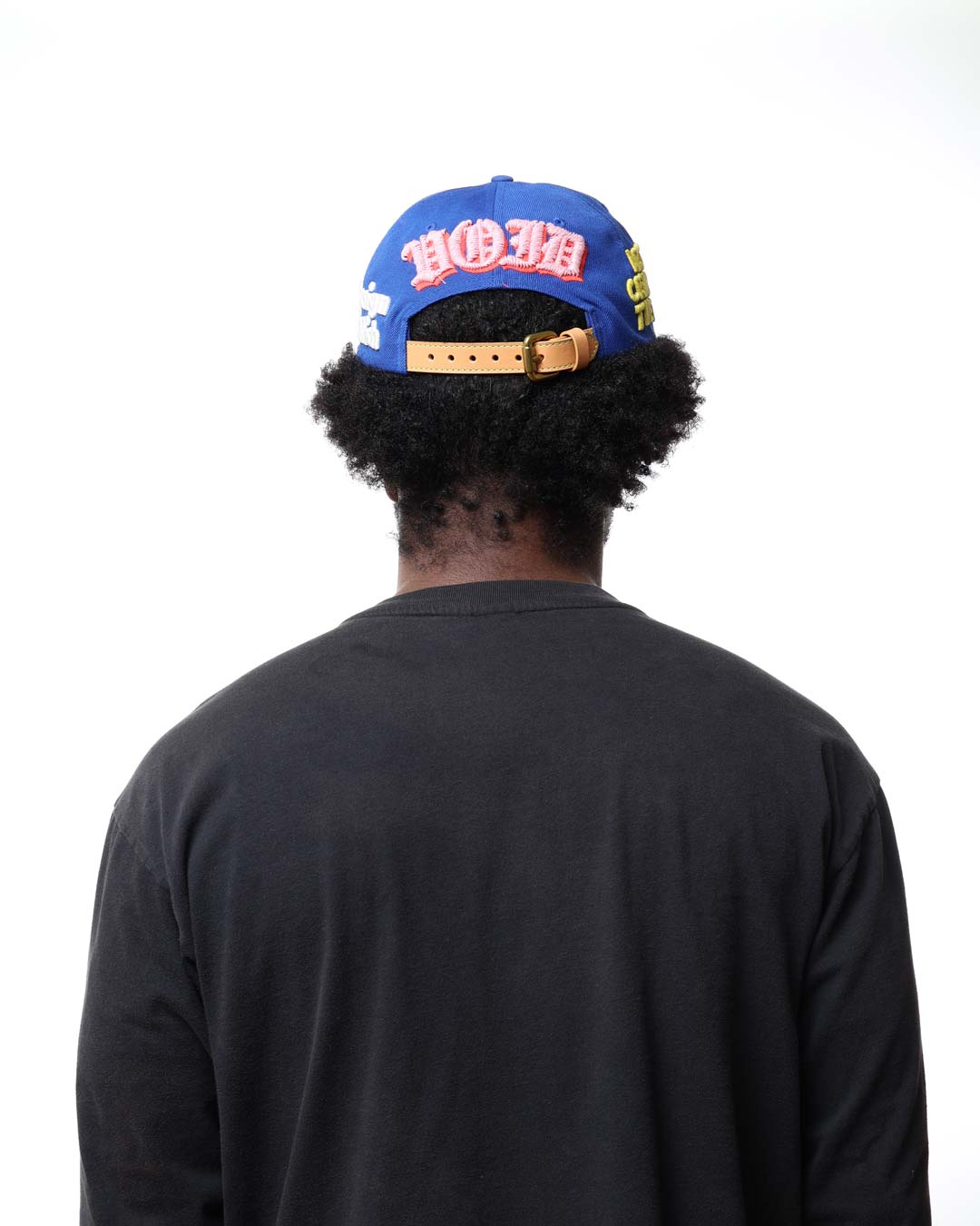 Person wearing a blue cap with colorful text on the back, facing away from the camera.