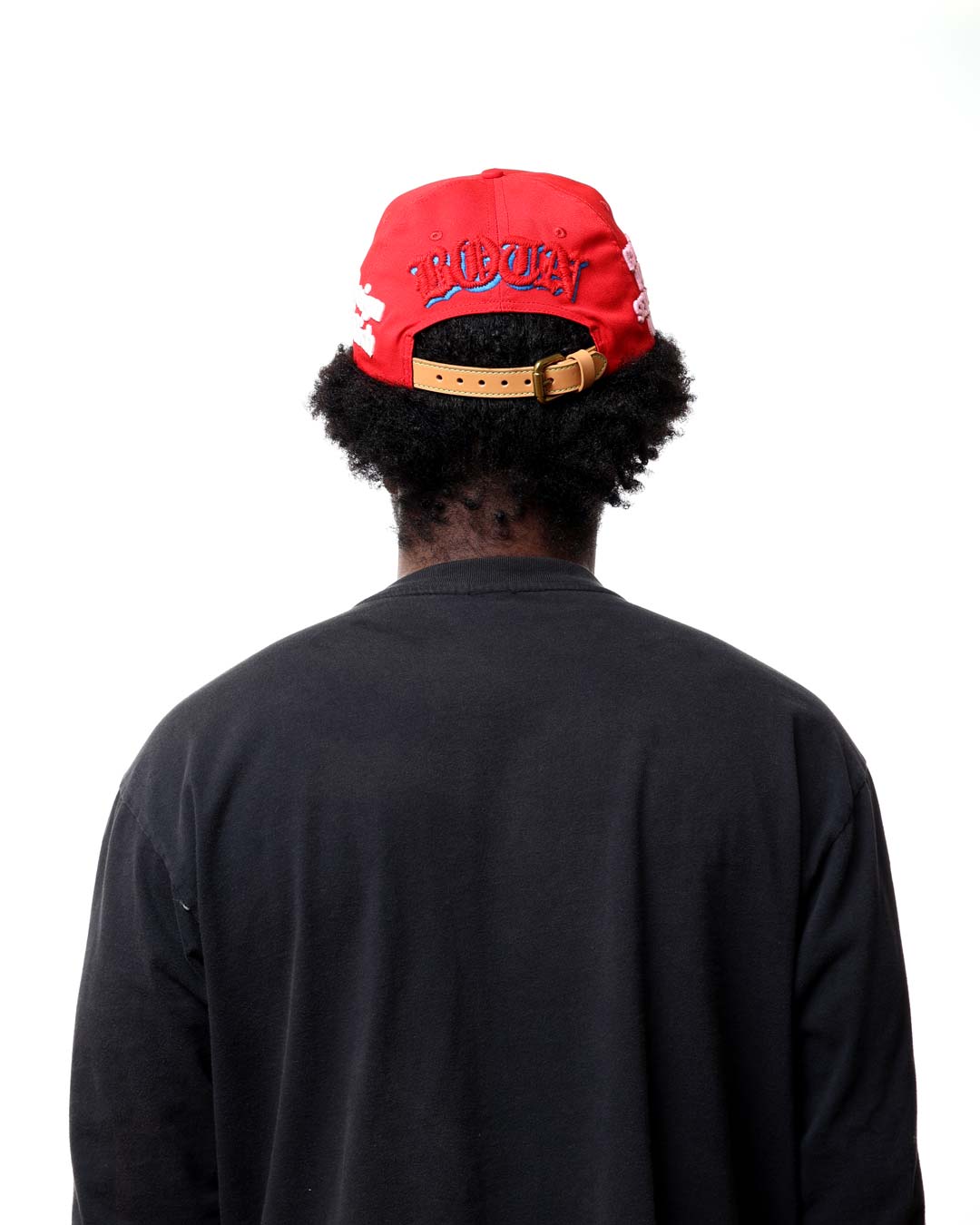 Person wearing a red cap with gold accents on a white background