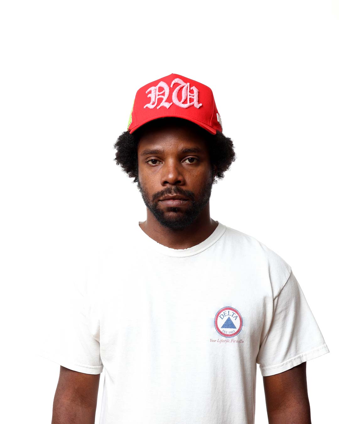 Man wearing a red cap with white text and a white t-shirt with a logo on a white background