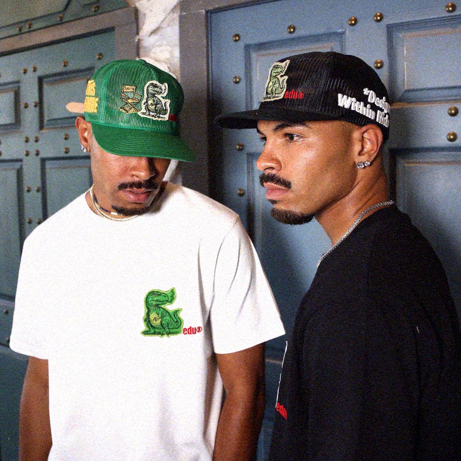 Two men in graphic t-shirts and embroidered caps.