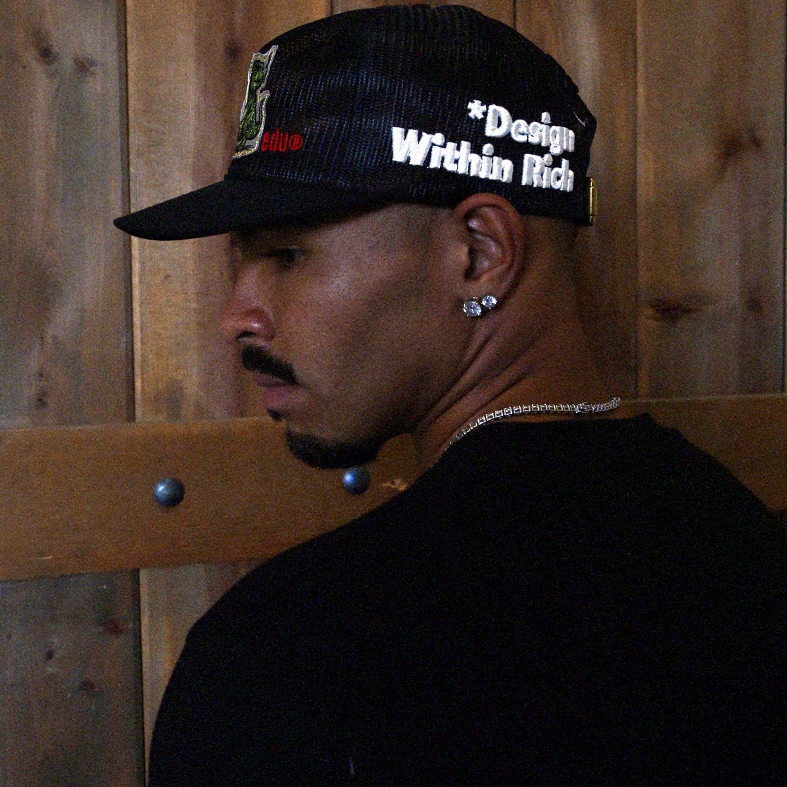 Black mesh cap with embroidered text and strap.