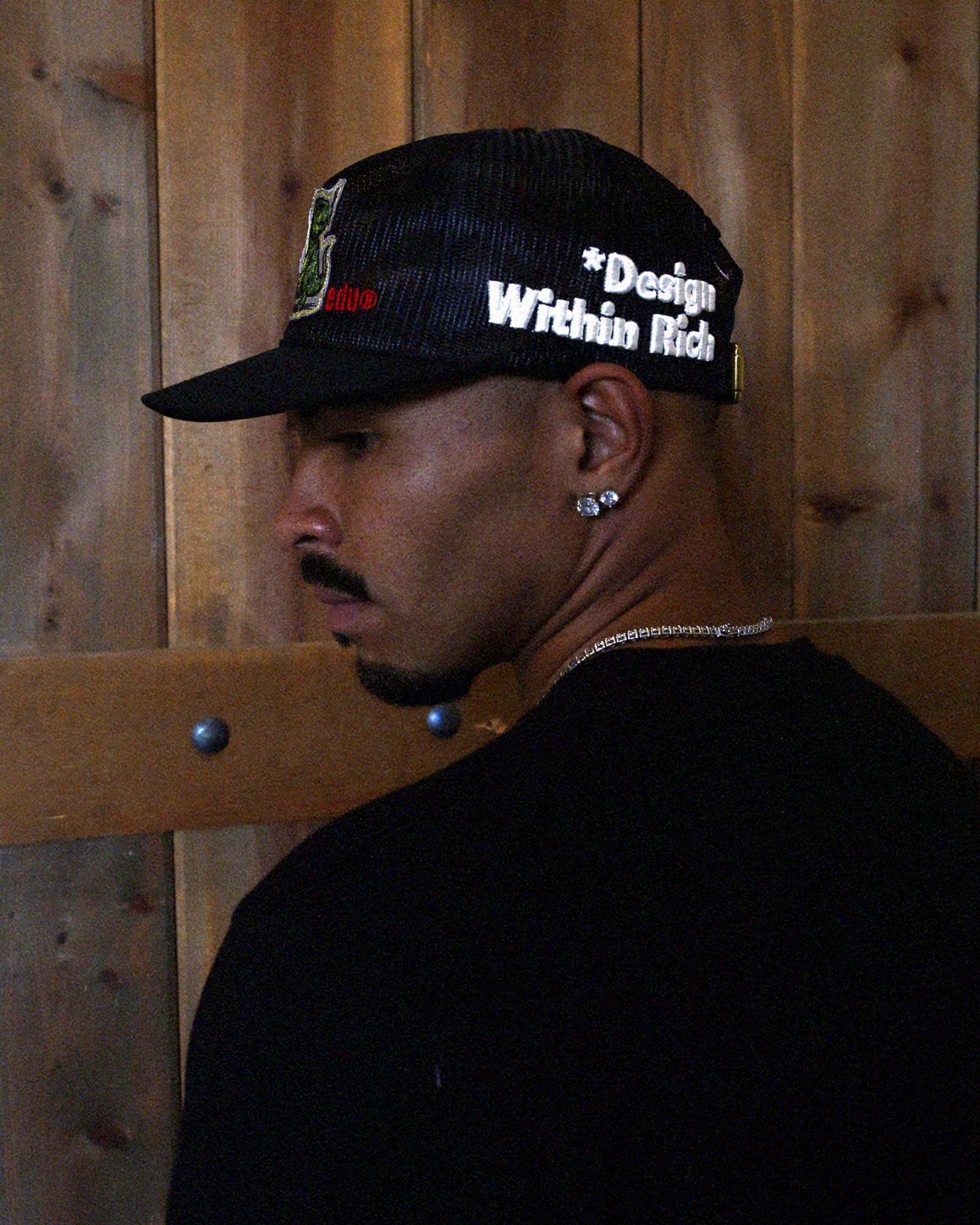Black mesh cap with embroidered text and strap.