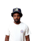 Man wearing a cap and white t-shirt with a logo on a white background